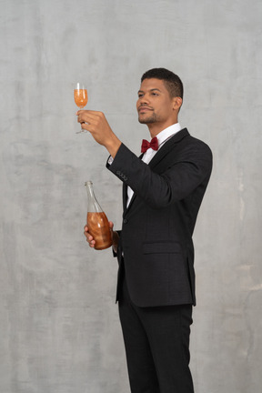 Young man raising a champagne glass and looking at it