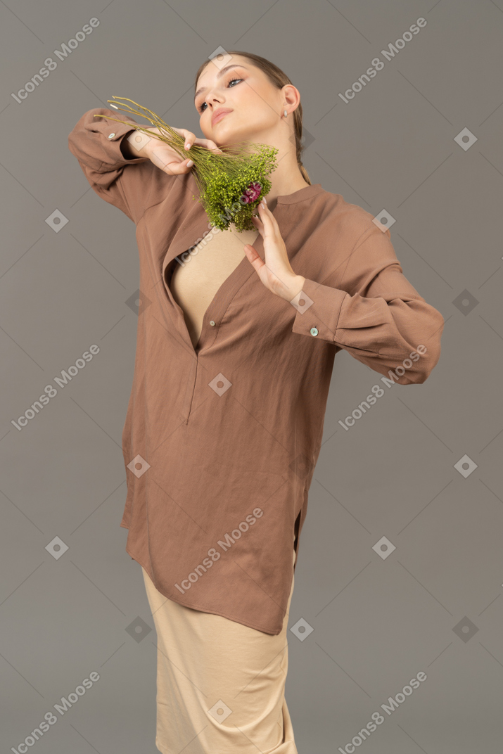 Giovane donna che tiene un mazzo di fiori sotto il mento
