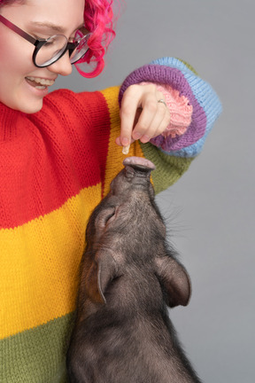 A woman feeding a tiny pet pig from her hands