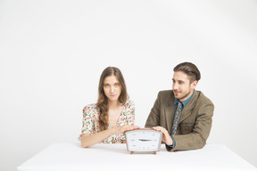 Couple assis à la table et tenant une horloge