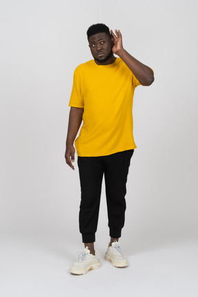 Front view of a young dark-skinned man in yellow t-shirt standing still