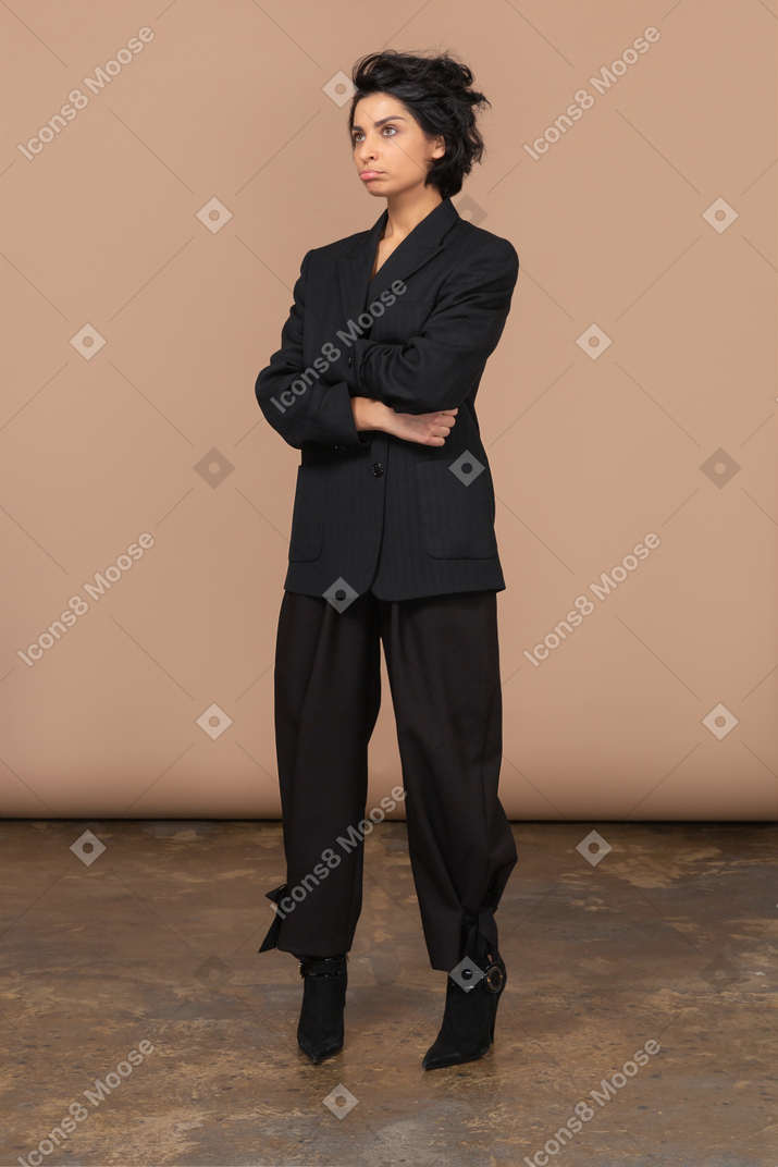 Three-quarter view of a pouting businesswoman crossing hands and looking up