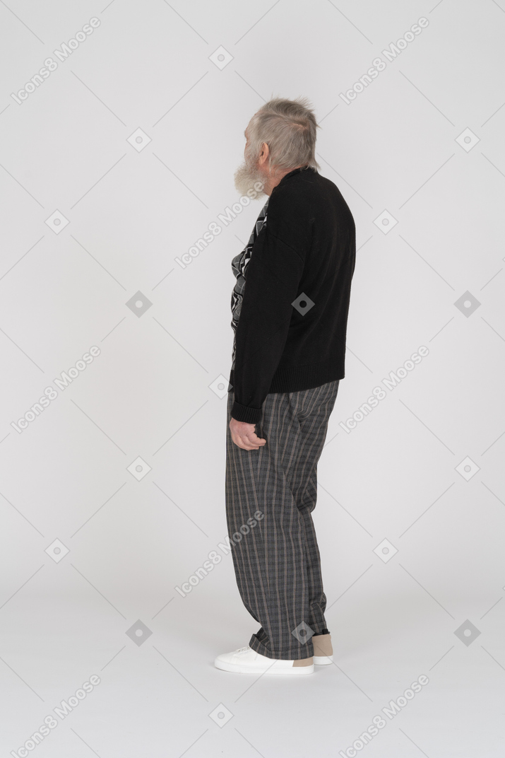 一位老人站着看着别处的侧视图