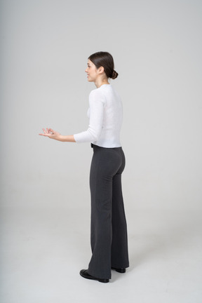 Vista laterale di una donna in pantaloni neri e camicetta bianca che gesticola