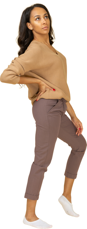 Vue latérale d'une jeune femme à la peau sombre mettant la main sur la hanche tout en regardant de côté