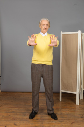 Front view of a displeased old man outstretching his hand