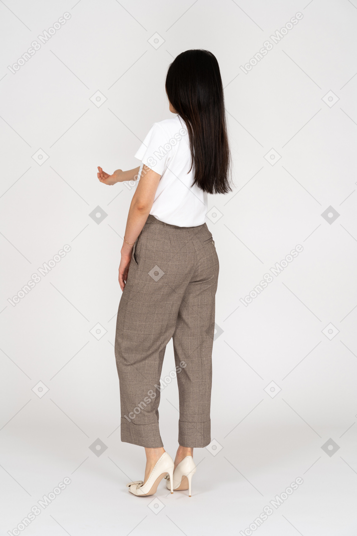 Three-quarter back view of a young lady in breeches and t-shirt outstretching her hand