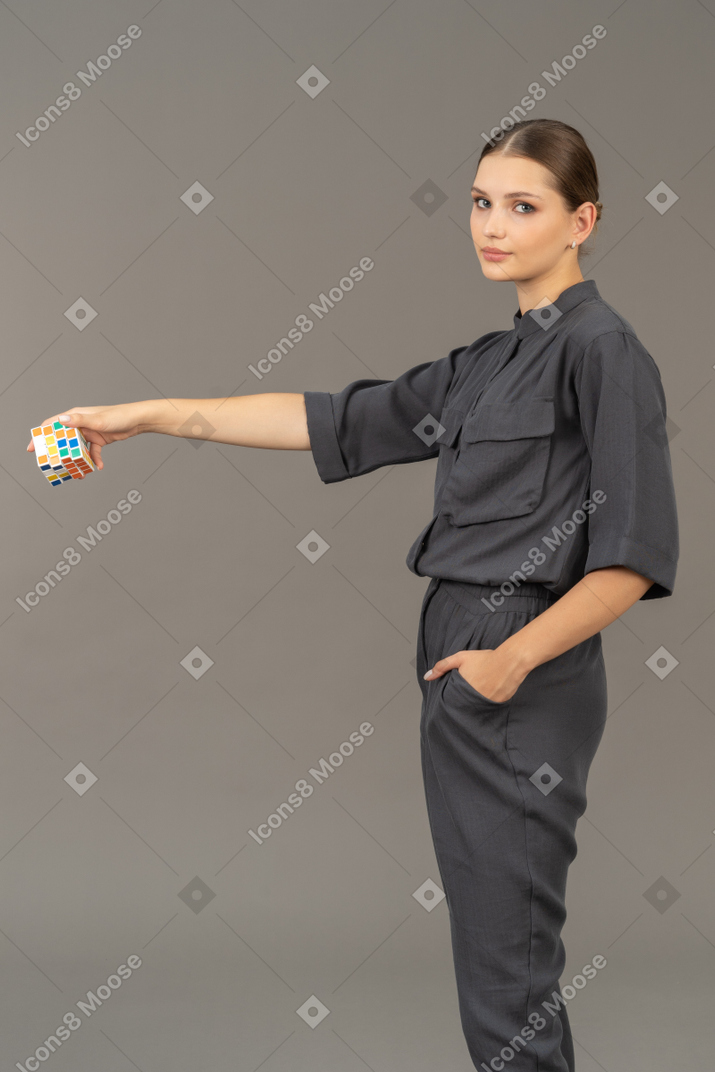 Vista di tre quarti di una giovane donna in tuta che tiene in mano un cubo di rubik