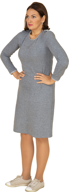 Vista frontale di una donna in abito grigio in piedi con le mani sui fianchi