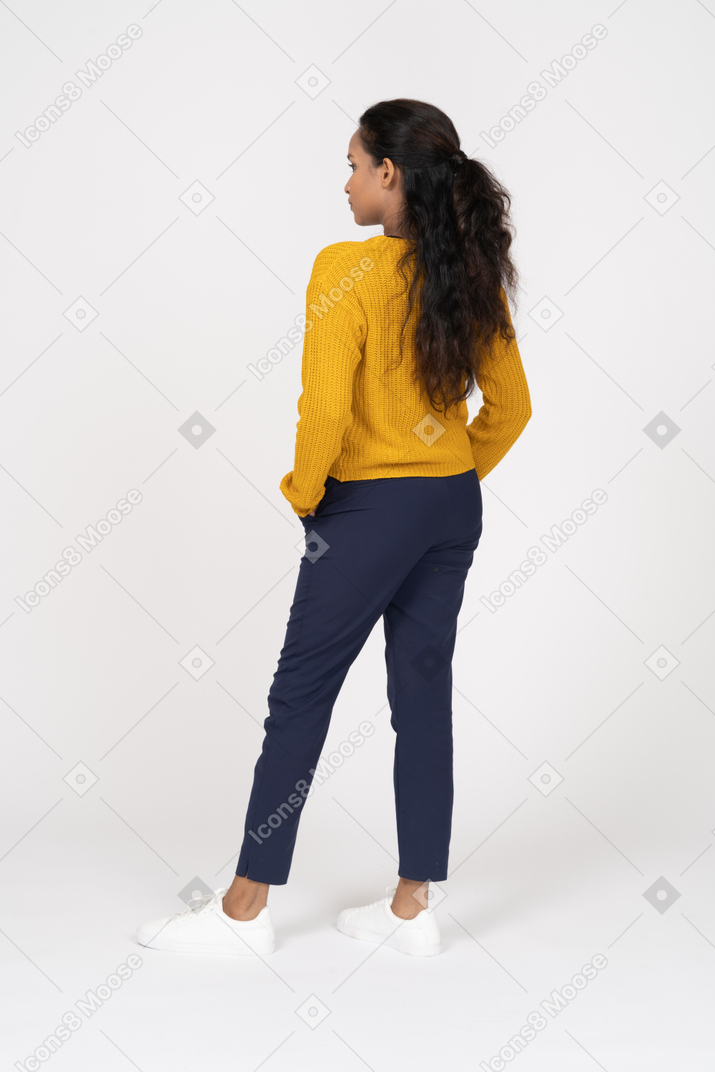 Vista posteriore di una ragazza in abiti casual in posa con le mani in tasca