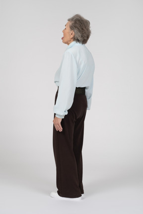 Rear view of an old woman sticking tongue out grudgingly