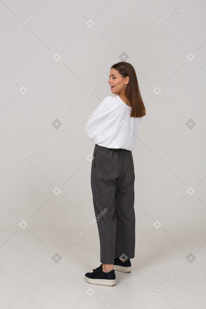 Vista posteriore di tre quarti di una bella giovane donna in abiti da ufficio che incrociano le braccia