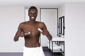 A man with a towel around his waist is brushing his teeth