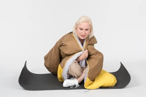 Mature woman sitting on tourist mat wrapped in blanket