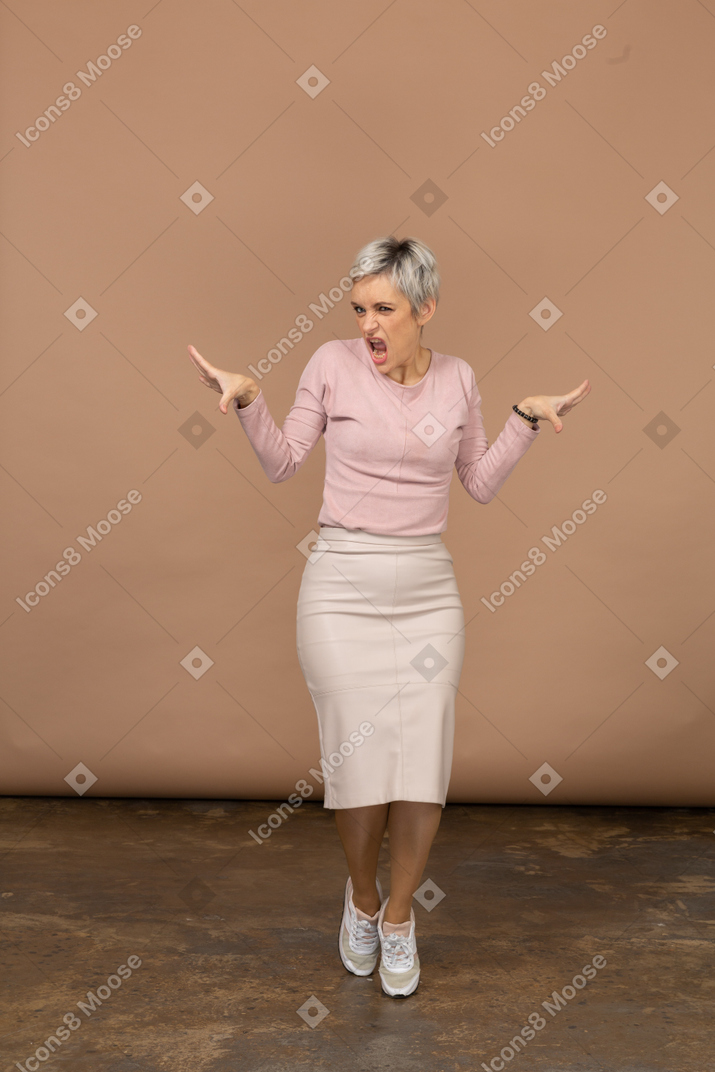 Вид спереди эмоциональной женщины в повседневной одежде, стоящей на цыпочках и протягивающих руки
