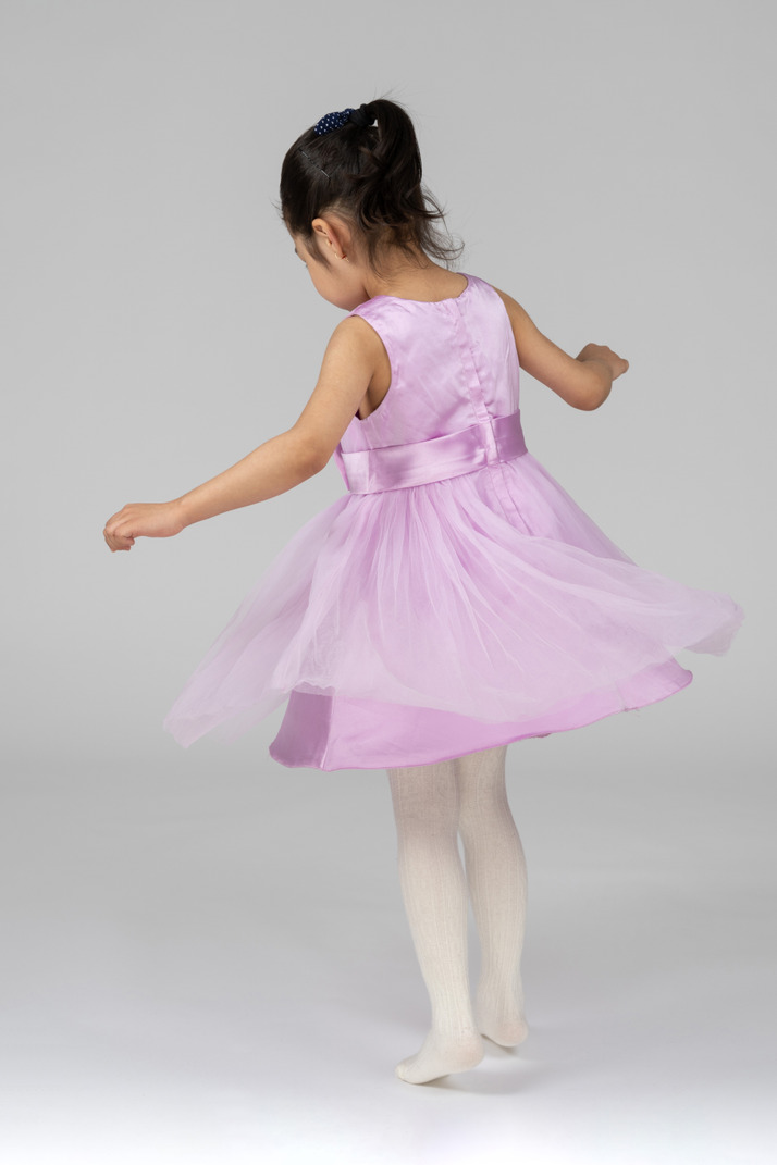 Back view of a girl in pink dress dancing