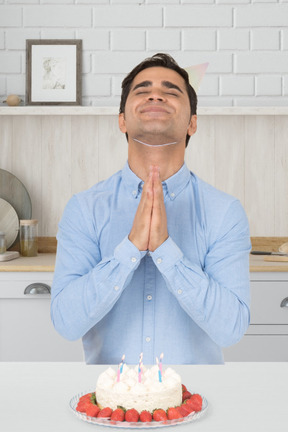 Man with folded hands celebrating birthday with cake