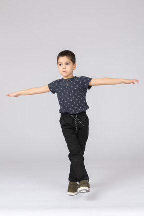 Vista frontale di un ragazzo carino in equilibrio su una gamba e braccia tese