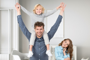 Boy sitting up on father's neck and girl standing near