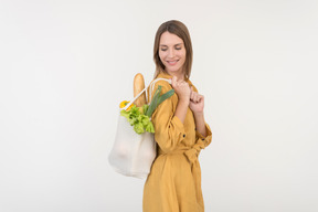Young woman holding shopping bag with vegetables and looking down