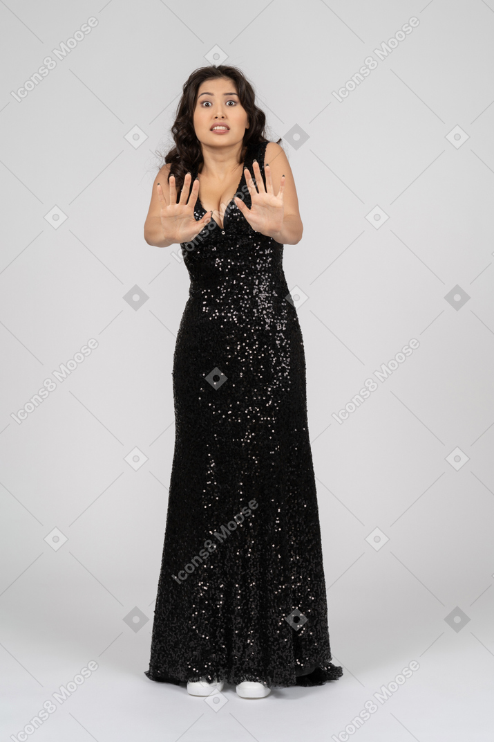 誰かを止めようとしている黒いイブニングドレスでおびえたアジア女性