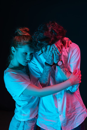 A couple standing under neon lights giving a support