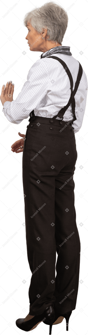 Three-quarter back view of a gesticulating unwilling old lady in office clothing