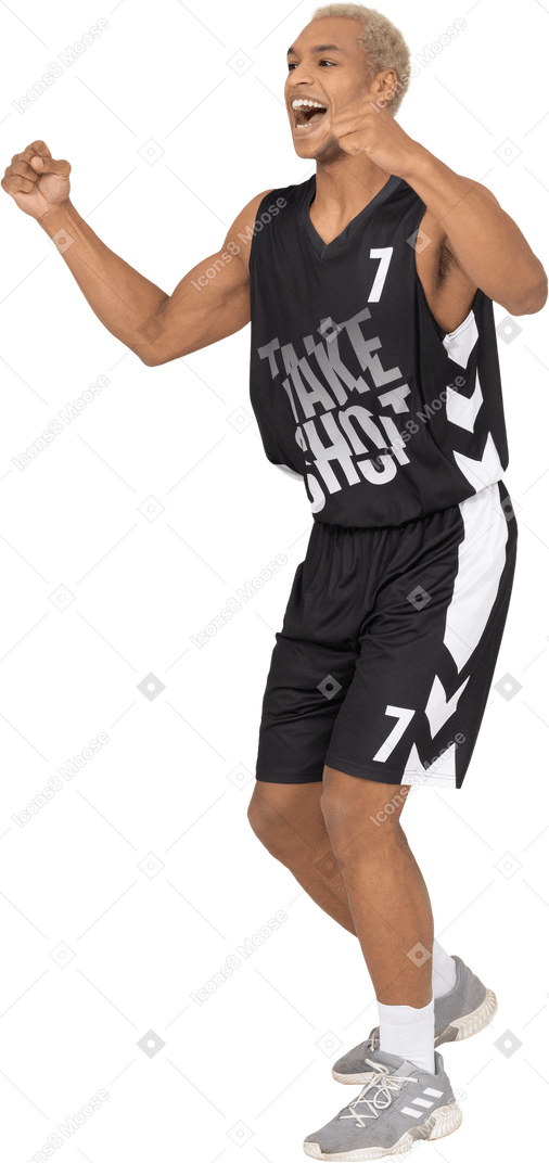 Vista de tres cuartos de un joven jugador de baloncesto masculino feliz levantando las manos