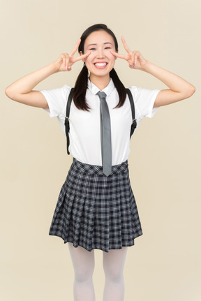Asian school girl showing v sign with both hands