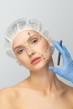 A woman in a surgical cap getting her face marked