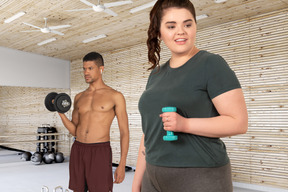 A man and a woman in a gym holding dumbbells
