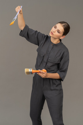 Woman in gray coveralls choosing a paint brush