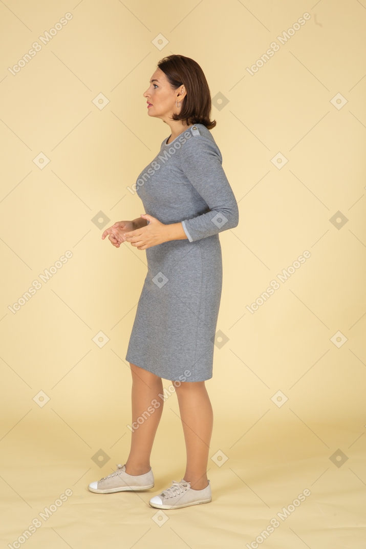 Vista lateral de uma mulher de vestido cinza