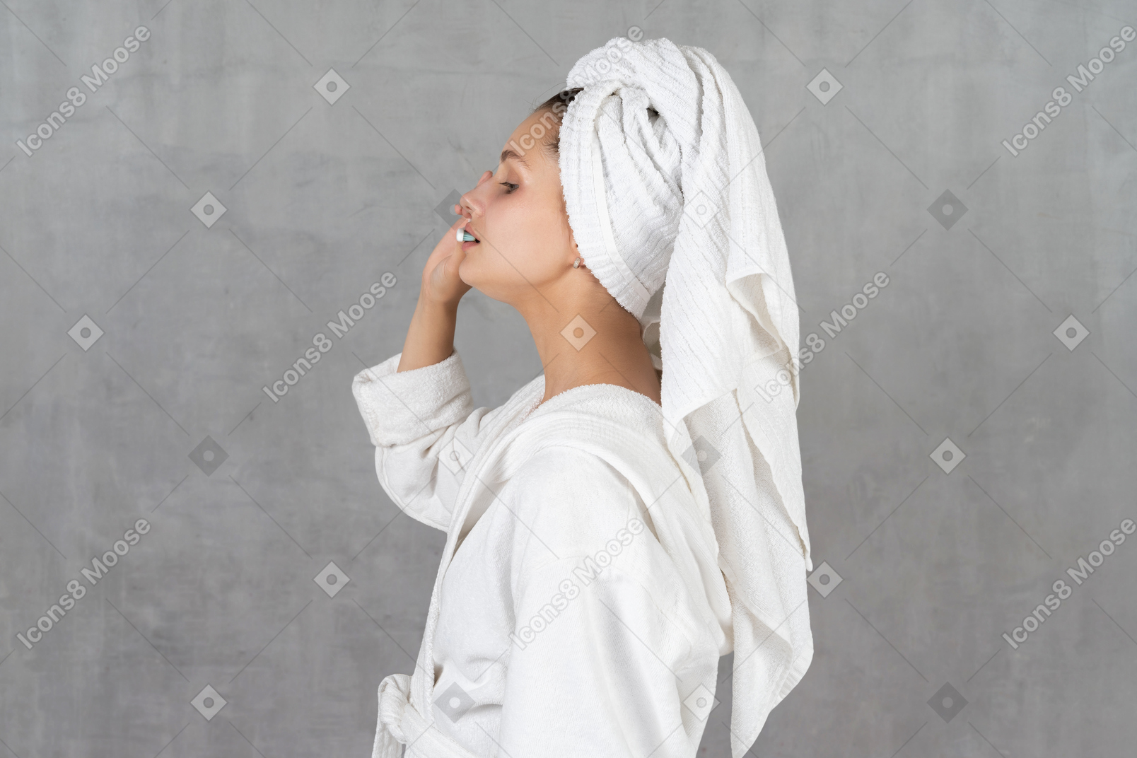Side view of a woman in bathrobe brushing her teeth