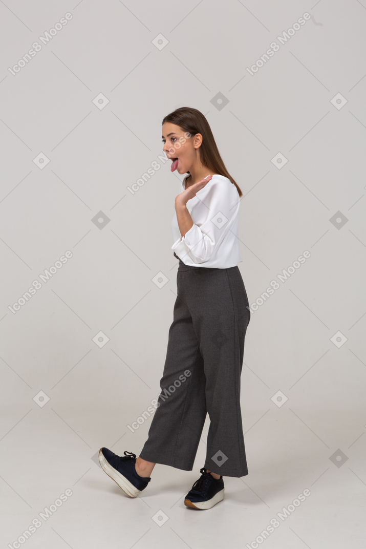 Three-quarter view of a young lady in office clothing showing tongue and raising hand