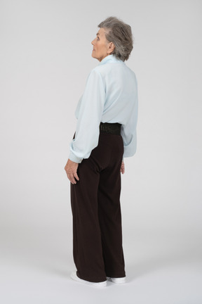 Vista posteriore di tre quarti di una donna anziana leggermente appoggiata all'indietro