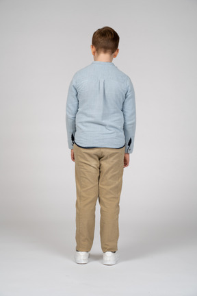 Rear view of a boy in casual clothes looking down