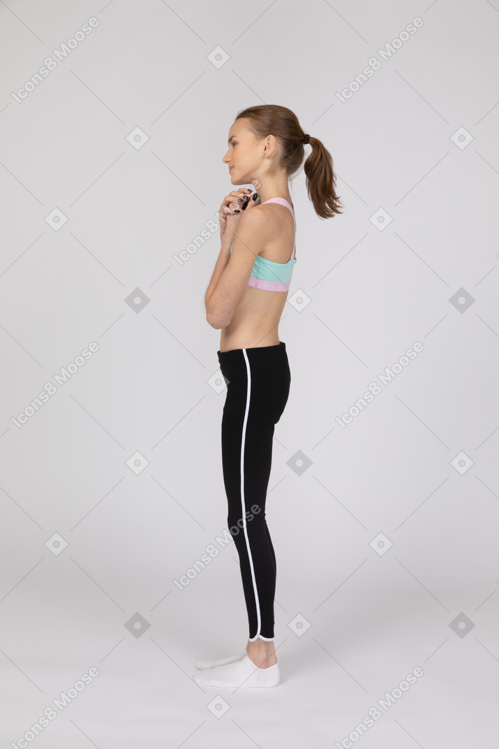 Vista lateral de uma adolescente em roupas esportivas levantando a mão e discutindo