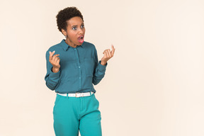 Black woman with a short haircut, wearing all blue, standing against a plain pastel background, looking emotional