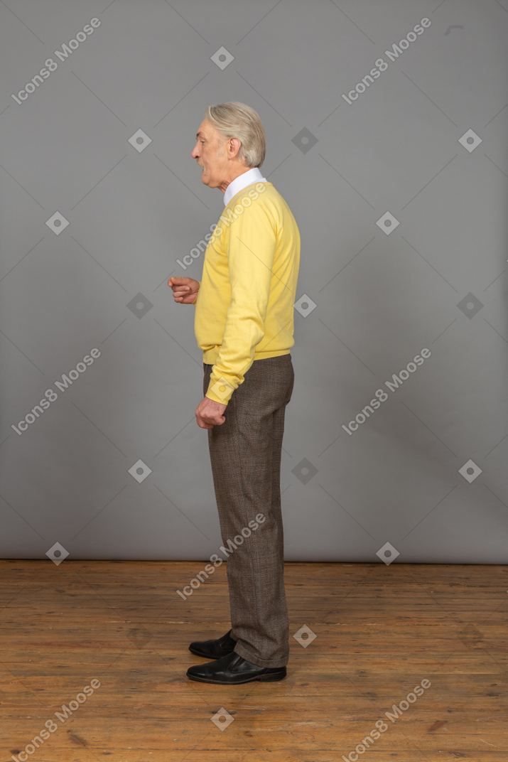 Vista lateral de un anciano hablando y gesticulando.
