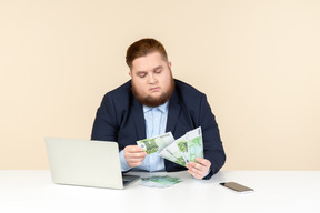 Молодой бизнесмен с избыточным весом сосредоточился на подсчете денег