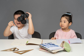 Niño riéndose mirando a través de binoculares junto a una niña