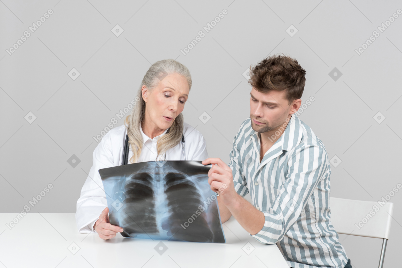 Doctora de edad explicando una radiografía a un paciente.