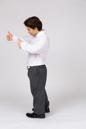Vista lateral de um homem em trajes formais, mostrando os polegares