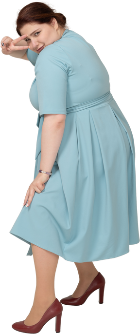 Vista laterale di una donna in abito blu che mostra il segno v