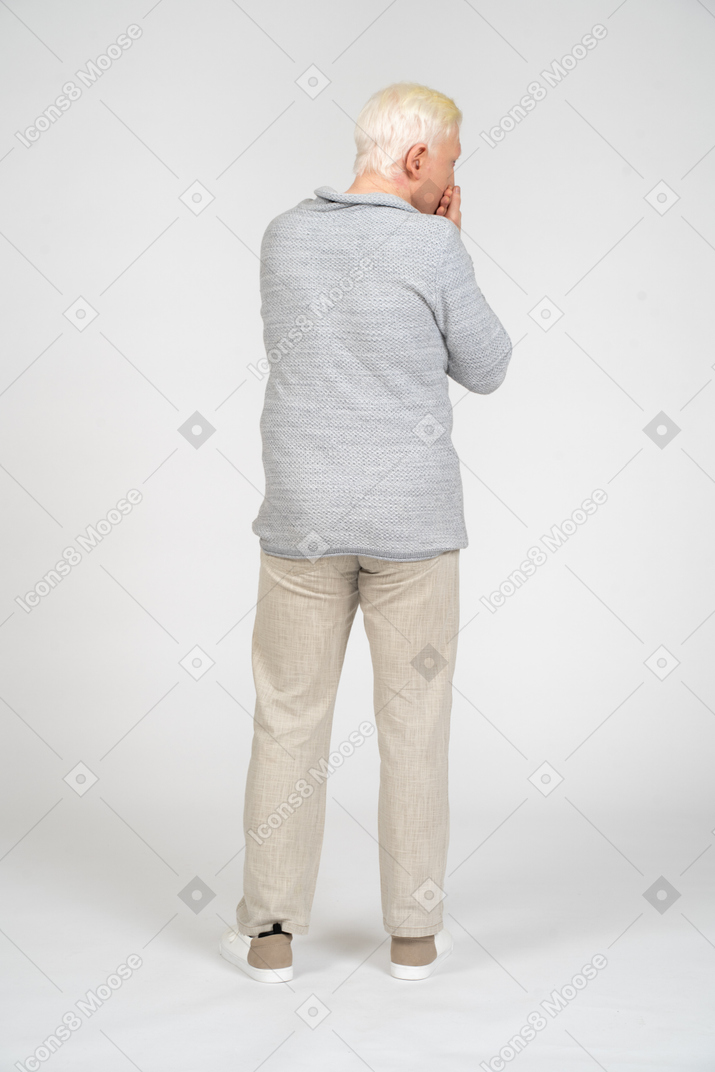 Back view of man covering his mouth with his hands