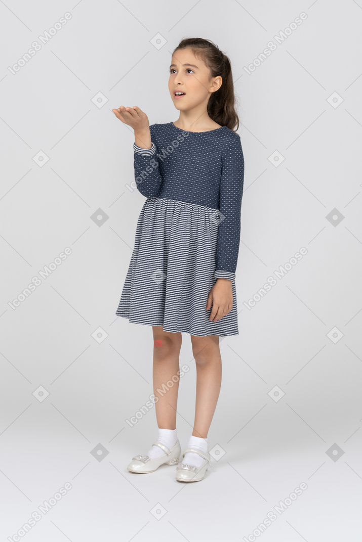 Vista de tres cuartos de una niña sorprendida extendiendo su palma