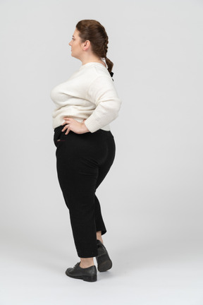 Mulher gorda com suéter branco posando com as mãos na cintura