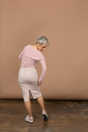 Вид сзади женщины в повседневной одежде, смотрящей на ее ногу