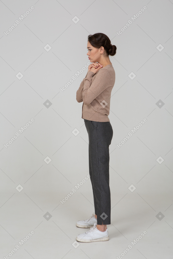 Vista laterale di una giovane donna preoccupata in pullover beige tenendosi per mano insieme